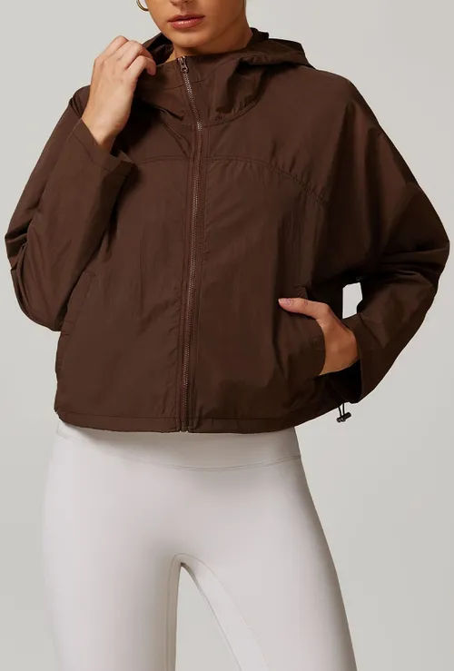 Veste coupe-vent sportive pour femmes avec poches zippées, capuche et cordon de serrage à la taille