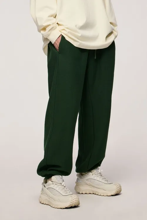 Pantalon de survêtement ample en molleton de couleur unie pour hommes, avec poches élastiques à la taille et jambes à larges poignets.